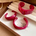Primo piano di bracciali aperti in acrilico marmorizzato rosso scuro - Rosa Rosso