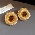Detailed macro view of vintage gold-plated round textured earrings with amber resin - Silver Post Amber Resin / Gold