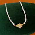 Close-up detail of 18K gold plated pearl necklace with shimmering zircon rhombus pendant - Choker Necklace / Gold
