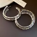 Primer plano de pendientes de aro en forma de C plateados con textura plisada - Estilo de Pasador de Plata / Plateado