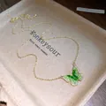 Exquisite close-up view of a green crystal butterfly pendant necklace with zircon inlay - Gold-Green