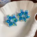 Makroaufnahme eleganter blauer Kristallblumen-Ohrstecker mit funkelnden Facetten - Blau