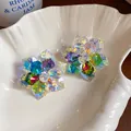 Gros plan sur des boucles d'oreilles fleurs en cristal coloré aux pétales facettés - Arc-en-ciel