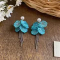 Elegant blue petal tassel earrings with white pearls on a rustic wooden background - Petal Tassel Style / Blue