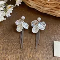 Detailed view of white iridescent petal tassel earrings with pearls on wooden background - Petal Tassel Style / White