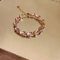 Close-up of pink pear-cut zirconia bracelet reflecting on a gold mirror surface - Bracelet - Gold / Pink