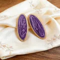 Nahaufnahme von violetten marmorierten ovalen Ohrringen mit goldenem Perlenrand - Stahlstift-Ohrstecker / Lila