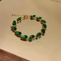 Close-up of elegant green teardrop zircon gems on a golden bracelet chain detail - Bracelet - Gold / Green