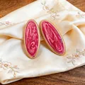 Detailansicht der ovalen Ohrstecker mit rosa marmoriertem Emaille und Goldrand - Stahlstift-Ohrstecker / Rosa