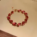Close-up of red teardrop zircon stones on elegant gold-plated bracelet detail - Bracelet - Gold / Rose Red