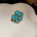 Close-up detail of vintage palace style flower earring with turquoise resin beads and gold finish - Ring / Blue