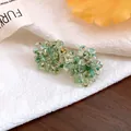Close-up of cluster bead earrings with teal glass spheres on white fabric background. - Pale Green
