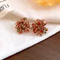 Macro detail view of handmade red and green glass cluster bead earrings on white linen texture - Light Red