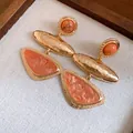 Detailansicht der geometrischen Harzohrringe mit goldener Hammerschlag-Metallstruktur. - Gold