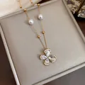 Close-up of elegant 18k gold plated necklace with zircon flower and pearl details - Gold