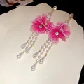 Close-up detail of pink mesh flower earrings with long pearl tassels and zircon accents - Pink