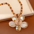 Détail d'un collier imposant avec des perles de verre orange et un pendentif fleur - Style Pendentif Fleur / Marron