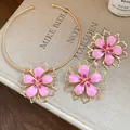 Close-up detail of elegant pink enamel flower choker and stud earrings set in gold. - Choker And Stud Earrings (HN11587) / Pink