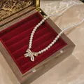 Elegant pearl necklace with crystal bow pendant displayed in a vintage wooden gift box - Gold-White