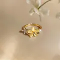 Detailed macro view of an exquisite gold ring featuring a yellow zircon flower and pearl - Gold