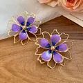 Close-up of elegant purple enamel flower earrings displayed on a rustic wood background - Silver Post Stud Earrings (HE32038) / Purple