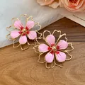Close-up detail of elegant pink enamel hollow flower earrings on wooden surface - Silver Post Stud Earrings (HE32038) / Pink