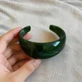 Nahaufnahme eines marmorierten grünen Acryl-Armreifs mit unregelmäßigem Design. - Armreif / Dunkelgrün