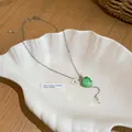Dettaglio di una collana con ciondolo a uva verde gelatina e fiore in un piatto a conchiglia. - Catena a Girocollo con Ciondolo a Uva / Tono Argento Verde