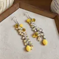 Close-up detail of yellow resin lemon tassel earrings with pearl and crystal beads - Silver-Yellow