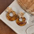 Close-up of vintage French amber resin hoop earrings with golden metal flowers - Silver Earring Post-Gold-Coffee