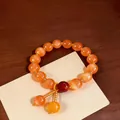 Primo piano di un bracciale vintage con perle occhio di gatto arancione su legno. - Arancione