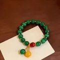 Primo piano di un braccialetto etnico vintage con pietre occhio di gatto verdi e perline - Verde