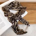 Detailed view of chiffon scarf with tiger and snake skin patterns tied in a bow - Coffee Python