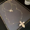 Close-up of elegant double-layer gold necklace with sparkling rhinestone flower pendants - Double Layer Necklace / Gold