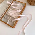 Sweet pink balletcore ribbon hair accessory elegantly draped over a wooden jewelry box - Pink