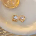 Detailaufnahme eleganter herzförmiger Ohrringe in Gold mit funkelnden Zirkonias - Gold