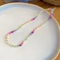 Gros plan d'un collier de perles de fleurs dopamine colorées sur une assiette blanche - Collier / Coloré