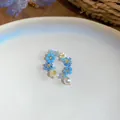 Gros plan d'une bague fleur en perles bleues faite main avec un pendentif perle blanche - Bague / Bleu-Blanc