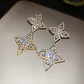 Detailed close-up of elegant gold flower drop earrings featuring sparkling zircon stones. - Gold