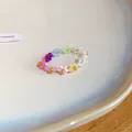 Gros plan d'une bague de fleurs en perles colorées avec des centres dorés - Bague / Coloré