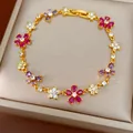 Detailed view of a gold-plated bracelet with multi-colored zircon flowers and butterfly charms - Gold-Magenta-Purple