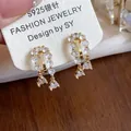 Close-up of elegant 18k gold plated zircon water drop ear clips on a jewelry display card - Clip-On Earrings / Gold