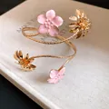 Nahaufnahme eines goldenen Armreifs mit rosa Emaille-Blumen und Gänseblümchen-Anhängern. - Blumen-Oberarmreif (HB5828) / Goldplattiert Rosa