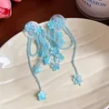 Close-up detail of blue glass flower tassel earrings on a textured ceramic plate - Blue