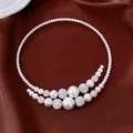 Close-up view of baroque pearl choker featuring rhinestone details on brown satin fabric - White