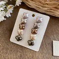 Close-up of shell-style flower drop earrings with an elegant gradient pearlescent finish - Gradient Tea Brown Green