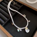 Detailed view of pearl necklace featuring zircon heart pendant and gold butterfly charms - Necklace-White-Pink