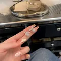 Vue détaillée des boucles d'oreilles nœud en argent avec pendentif zircon, tenues en main - Style Noeud / Argent
