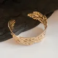 Detailed macro view of a gold-finish open cuff bracelet featuring an intricate leaf texture. - Gold (9#)