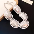 Detailed macro view showing the glossy pleated surface of the silver-toned oval link necklace - Necklace / Silver